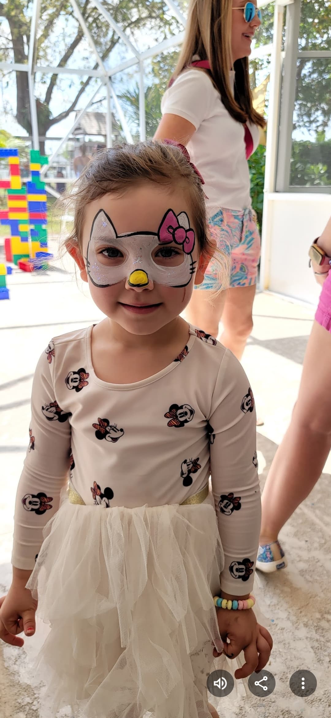 Young girl with Hello Kitty face paint wearing a Minnie Mouse shirt and tutu.